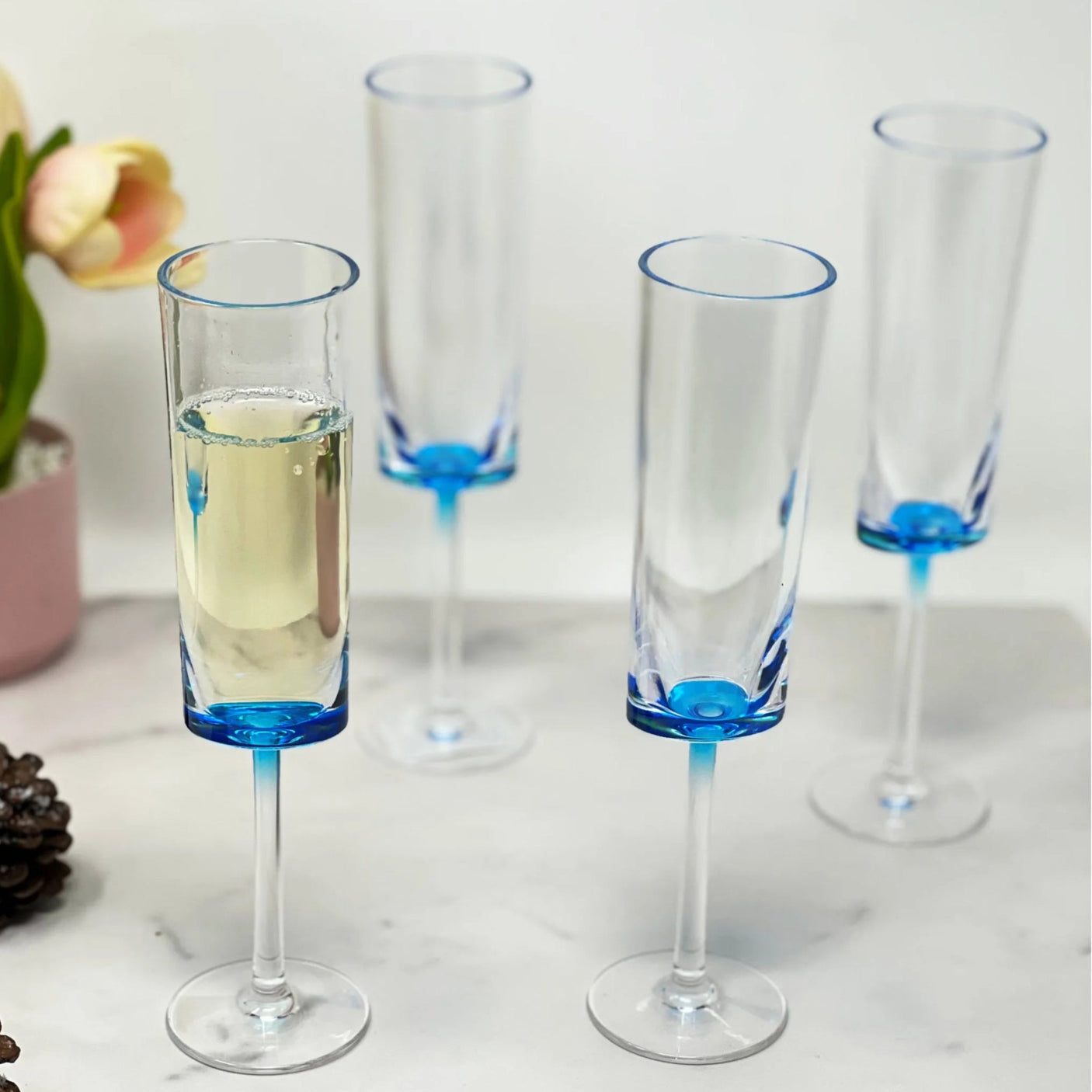 Set of four champagne flutes with blue accents on a marble surface.