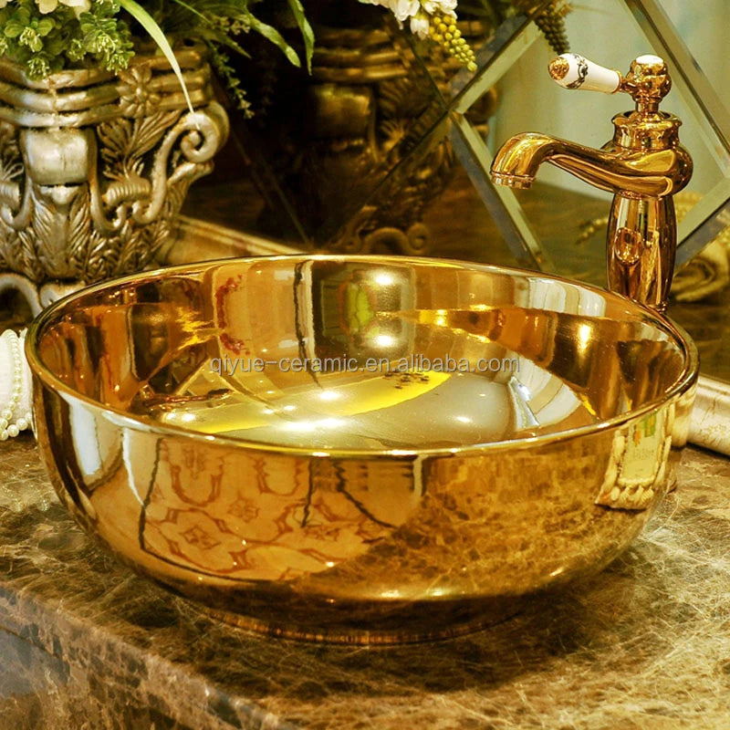 Gold sink basin with faucet on a marble surface