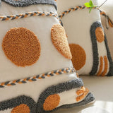 Decorative pillows with textured patterns and braided accents on a neutral background