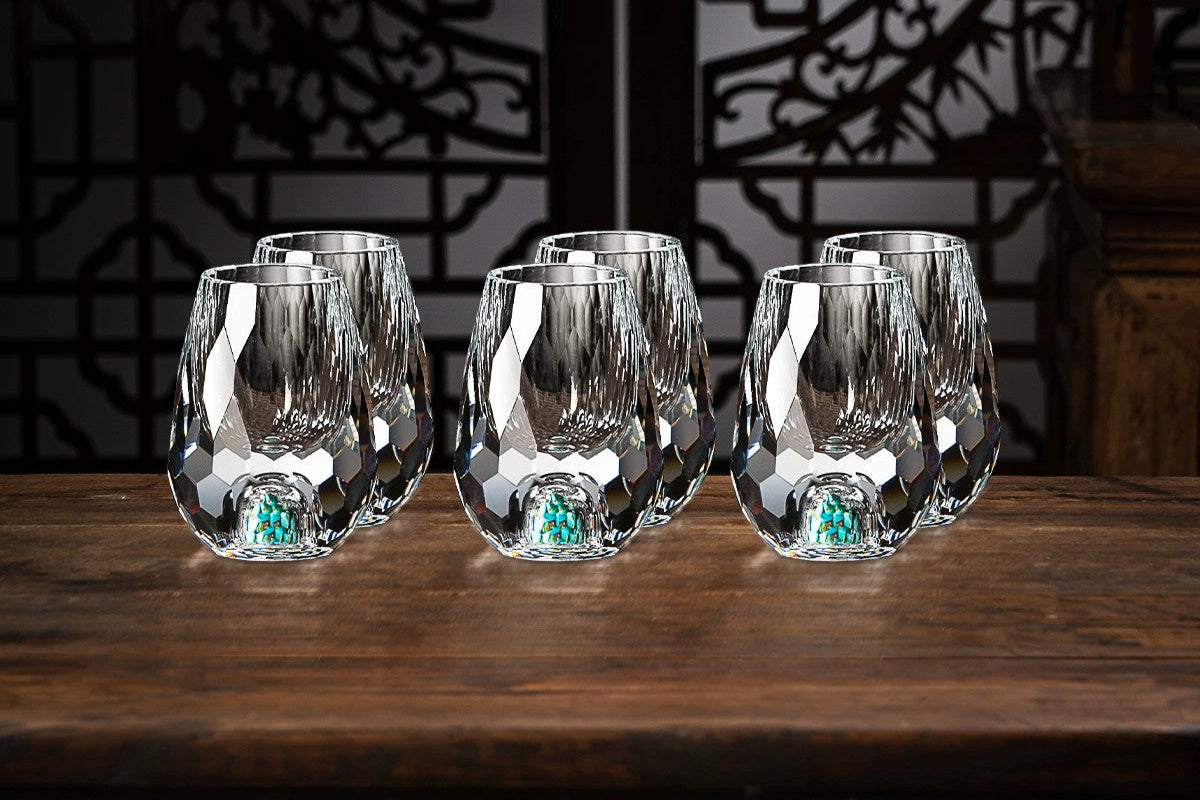 Set of six diamond-textured glasses on a wooden surface with a dark decorative background.
