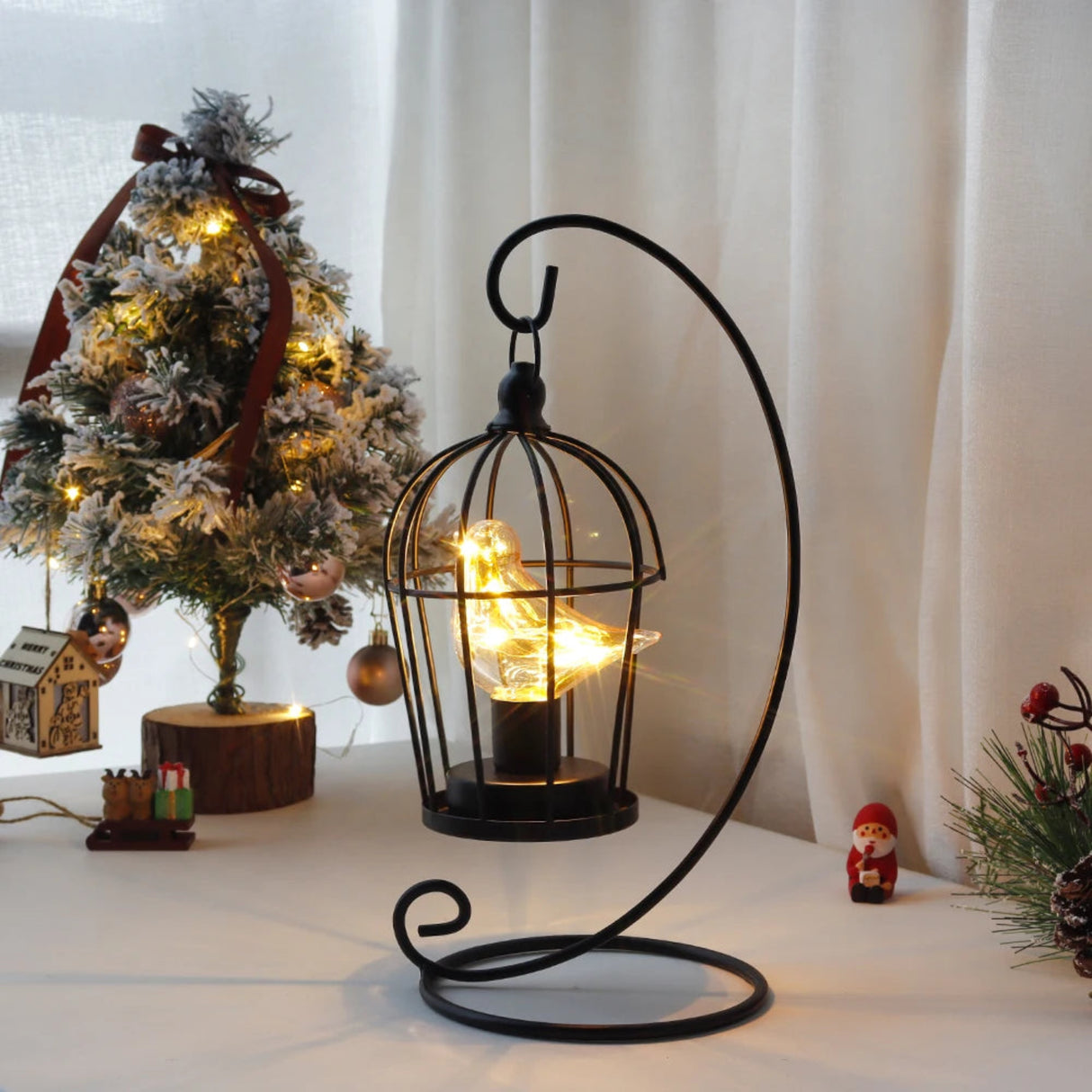 Decorative candle holder with a lit candle in front of a Christmas tree.