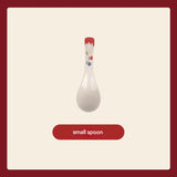 White ceramic spoon with floral design on a red handle against a beige background