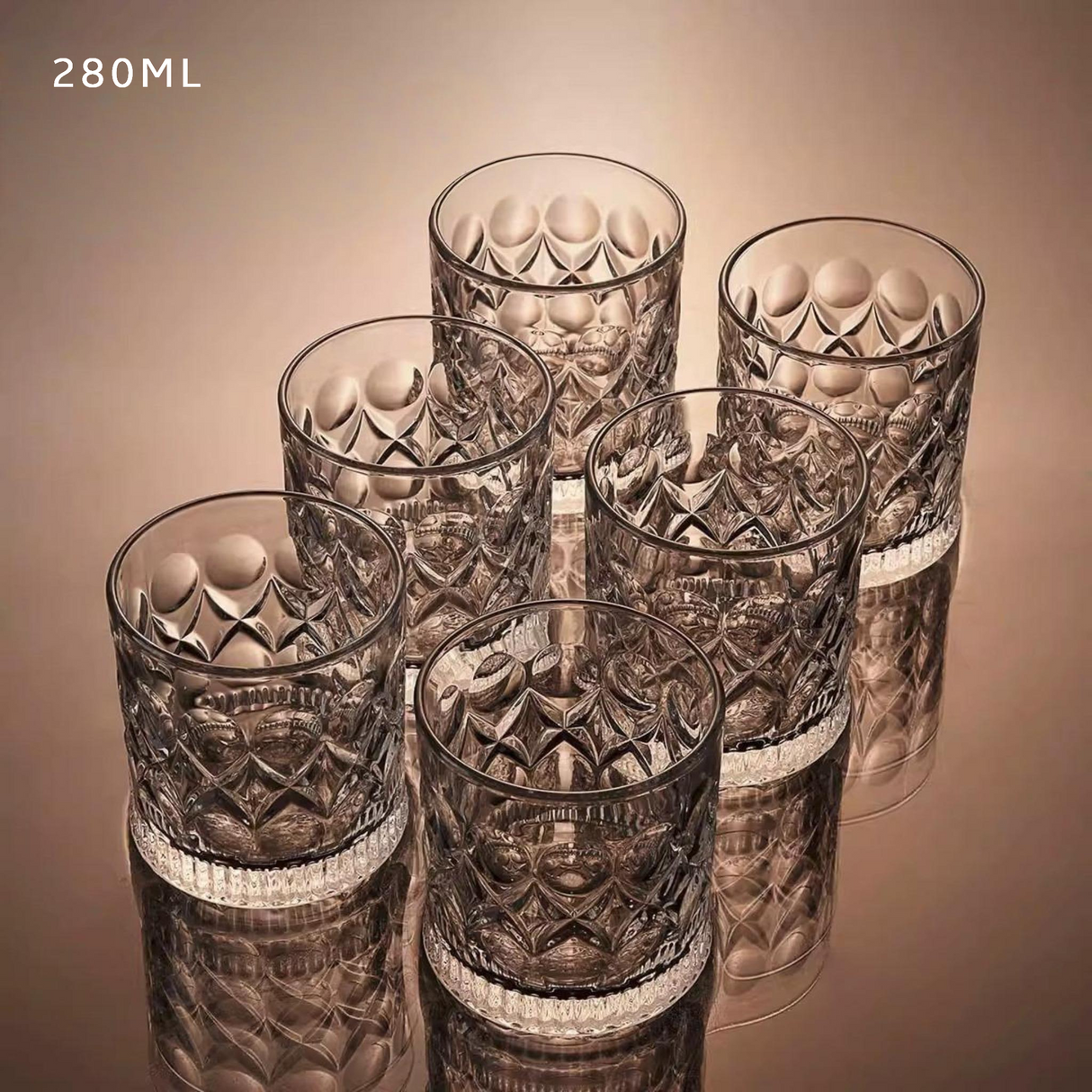 Set of six patterned glass tumblers on a reflective surface with a beige background.