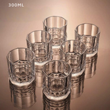 Set of six clear glass tumblers with textured design on a reflective surface.