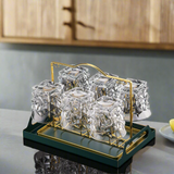 Set of clear glass tumblers with a gold stand on a kitchen counter.